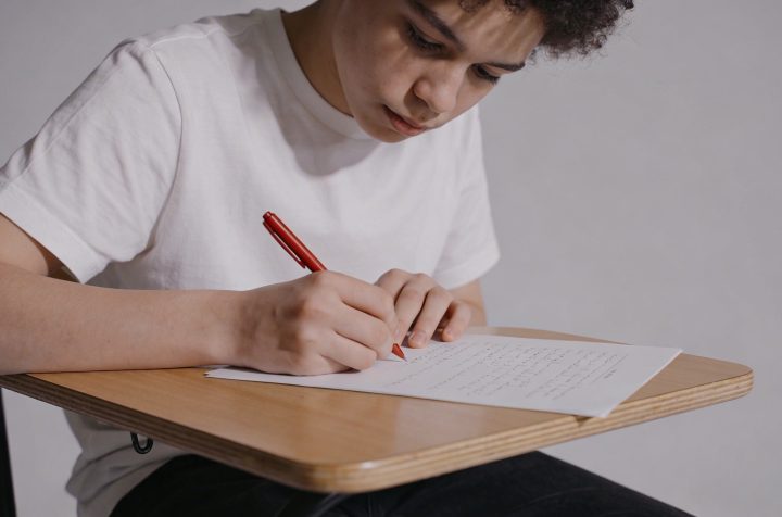 eleve assis corrige copie avec stylo rouge