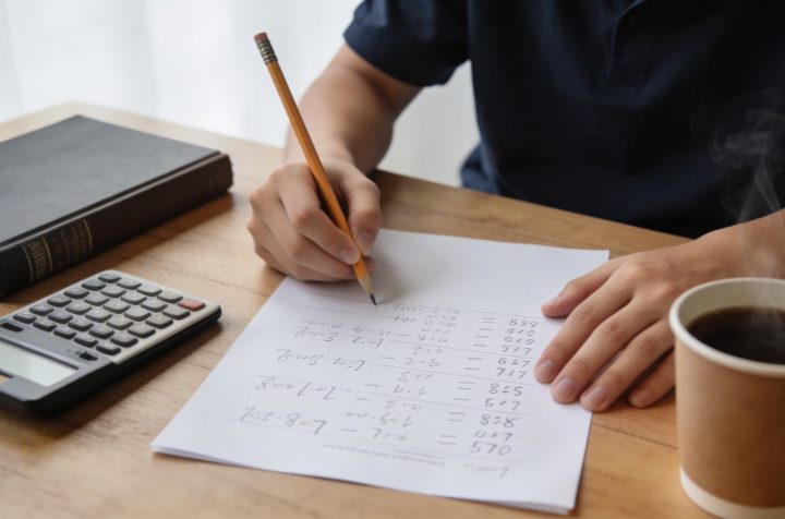 eleve assis a un bureau resolvant des calculs de notes sur une feuille