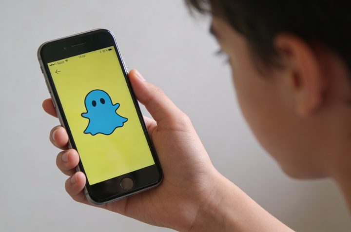 Main de teen affichant ecran Snapchat avec icone bleue