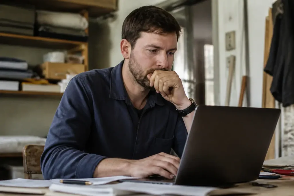 Artisan devant un ordinateur portable et des documents