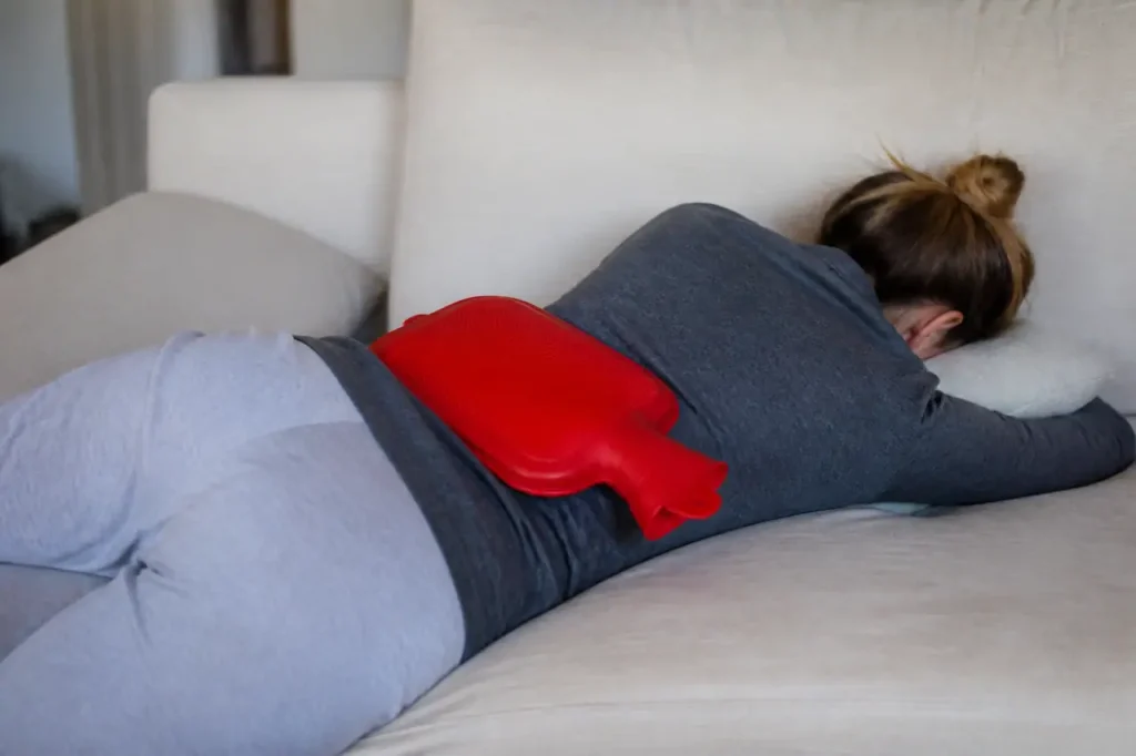 Bouillotte rouge posee sur le bas du dos