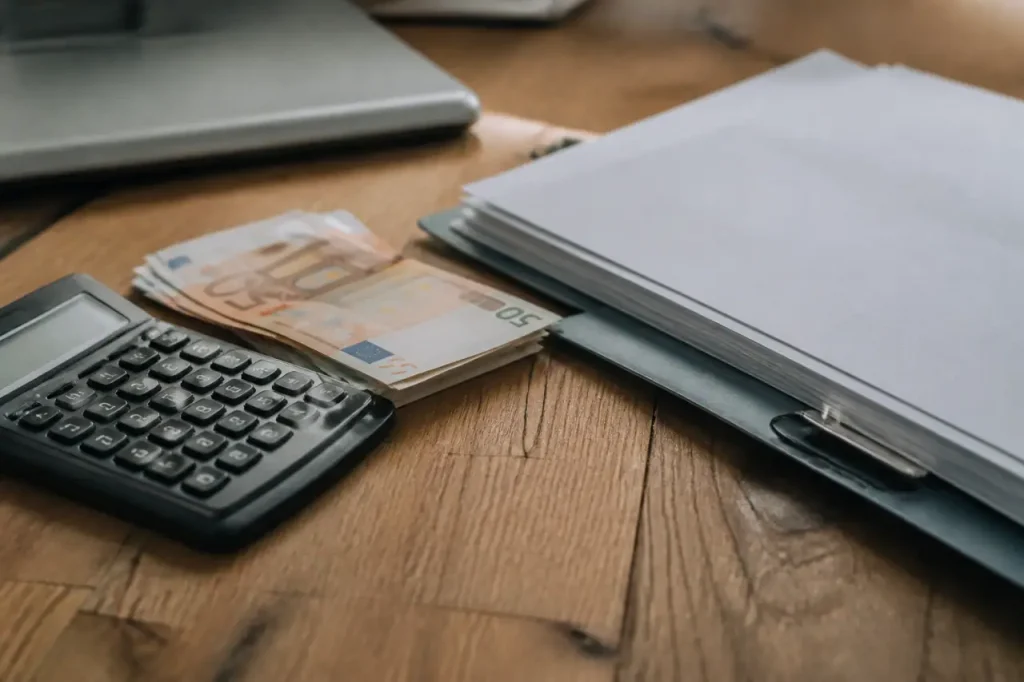 Calculatrice, billets et contrat de travail sur un bureau