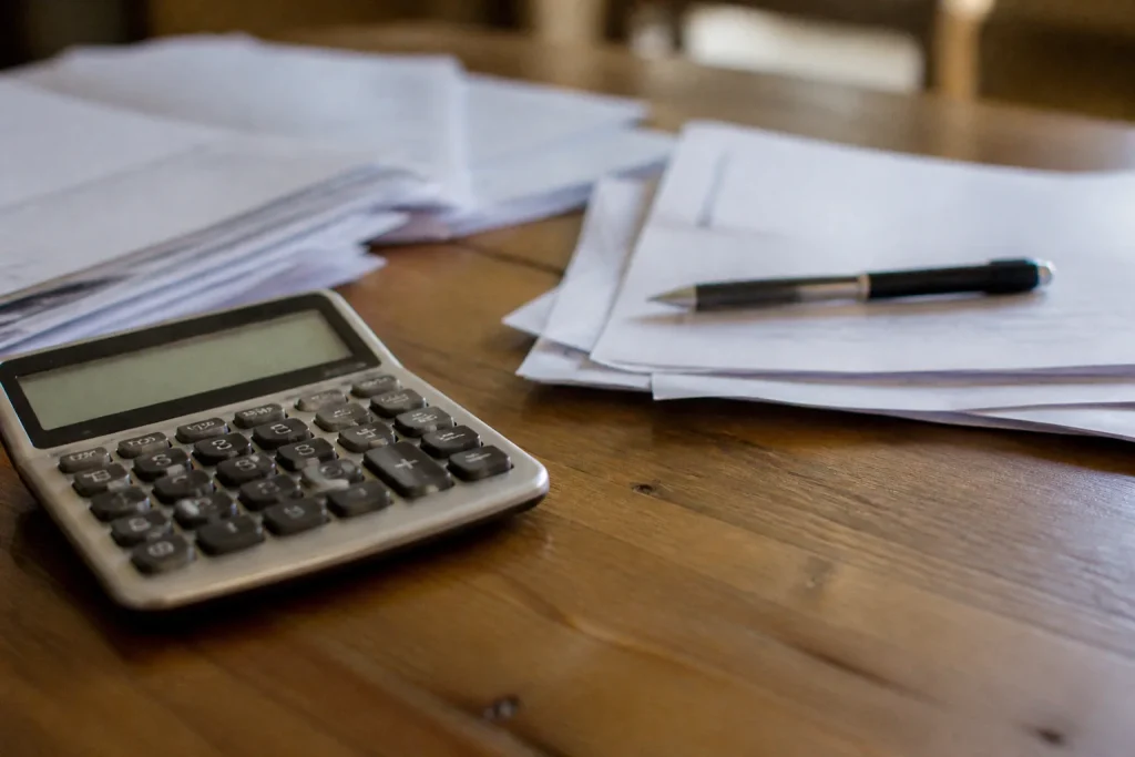 Calculatrice et factures sur bureau en bois avec stylo