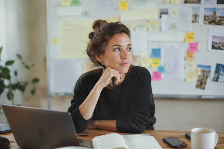 Entrepreneure assise devant un tableau blanc couvert de notes