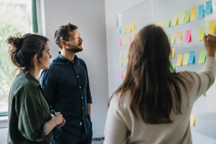 Equipe debout devant tableau blanc couvert de post-it