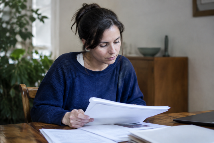Femme age consulte documents administratifs assise table