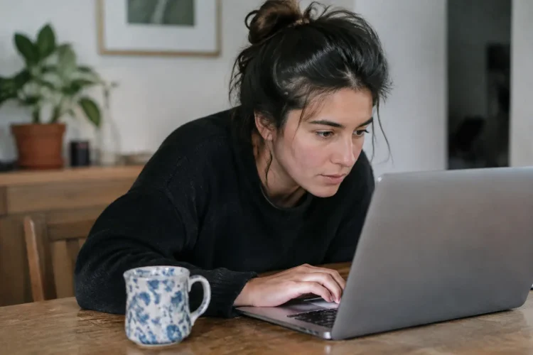 Femme assise penchée vers un ordinateur portable