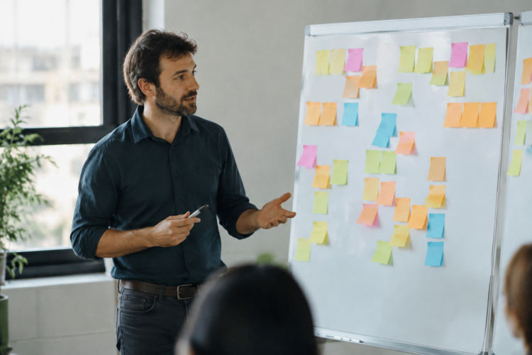Formateur debout devant un tableau blanc couvert de post-it