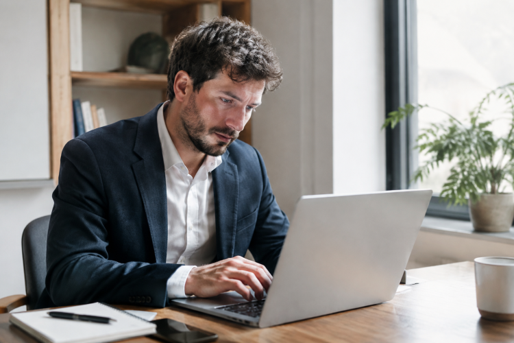 Homme d'affaires assis remplissant un formulaire sur ordinateur portable