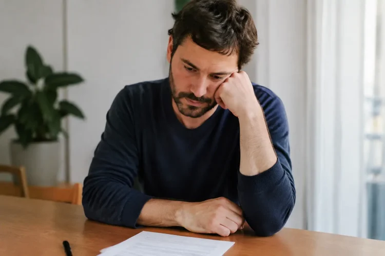 Homme assis tenant son coude droit devant un formulaire