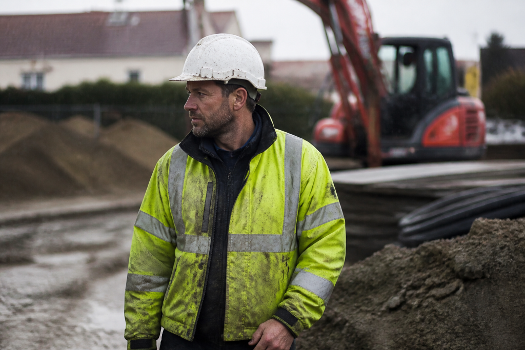 Ouvrier en gilet jaune sous la pluie sur chantier
