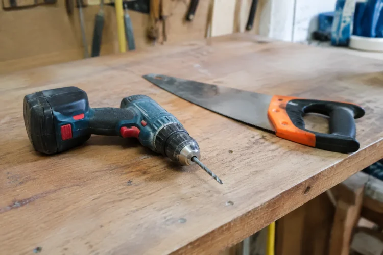 Perceuse et scie alignees sur un etabli en bois