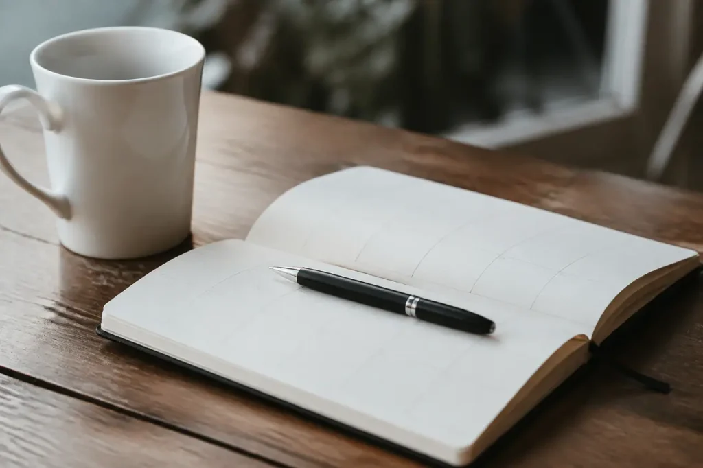Stylo noir et calendrier ouvert avec tasse blanche